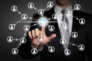 Ein Mann tippt auf einem Bildschirm mit vernetzten Symbolen eine Weltkugel an. | © Torbz - Fotolia.com