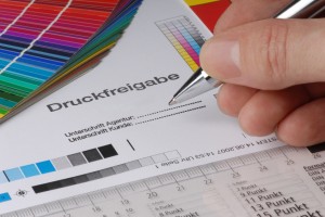 Proof mit Aufdruck "Druckfreigabe", davor eine unterschreibende Hand